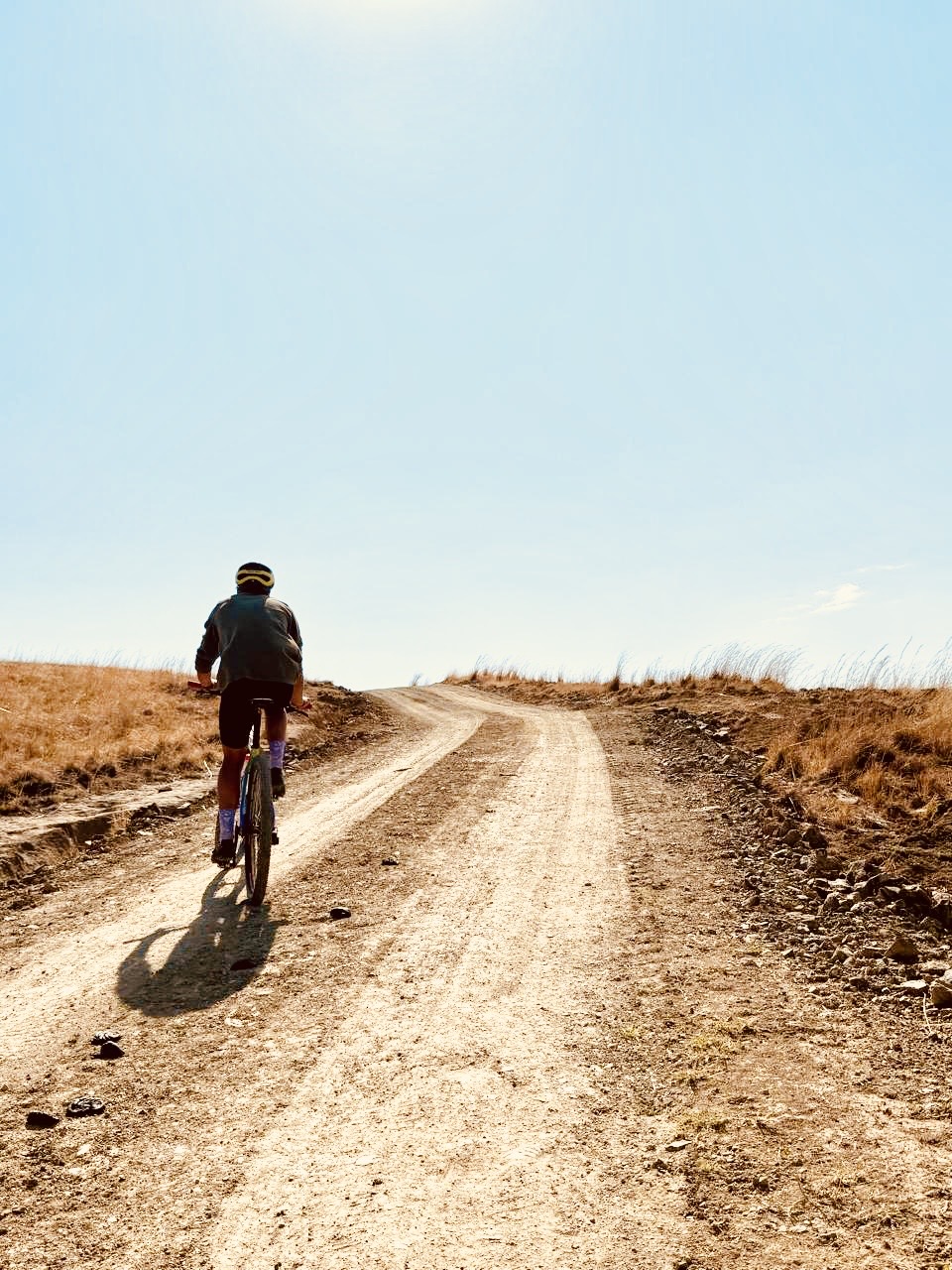 Mountain biker climbing a dirt road through dry grassland