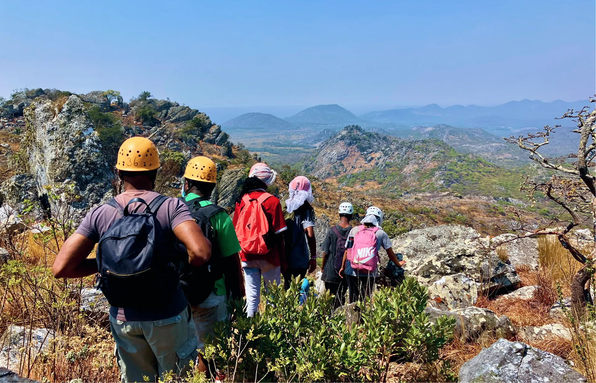 Hikers traversing a rocky mountain ridge above a wide valley