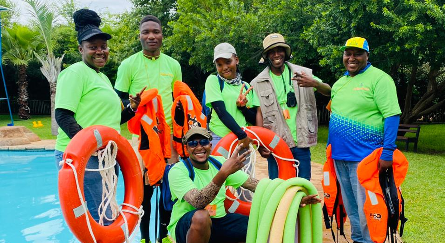 Water safety practitioners in life jackets beside a training pool