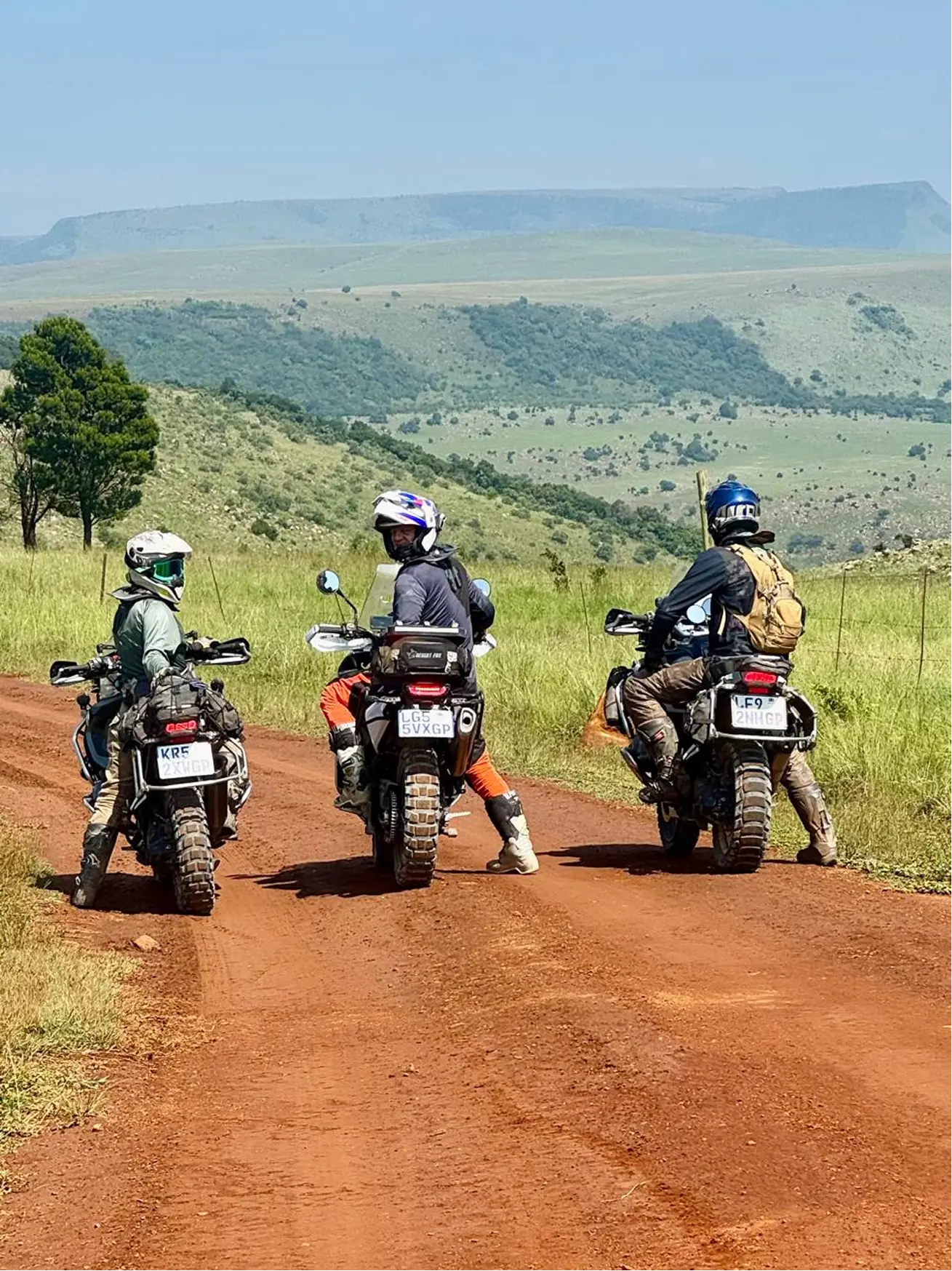 Adventure motorcyclists on a dirt road across a grassy plateau