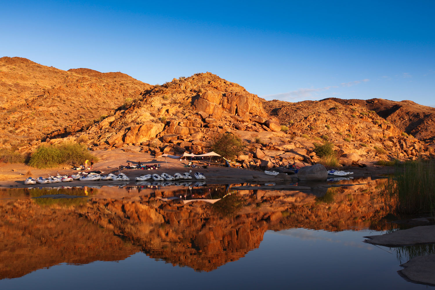 Sunrise over a riverside camp with rafts on the bank